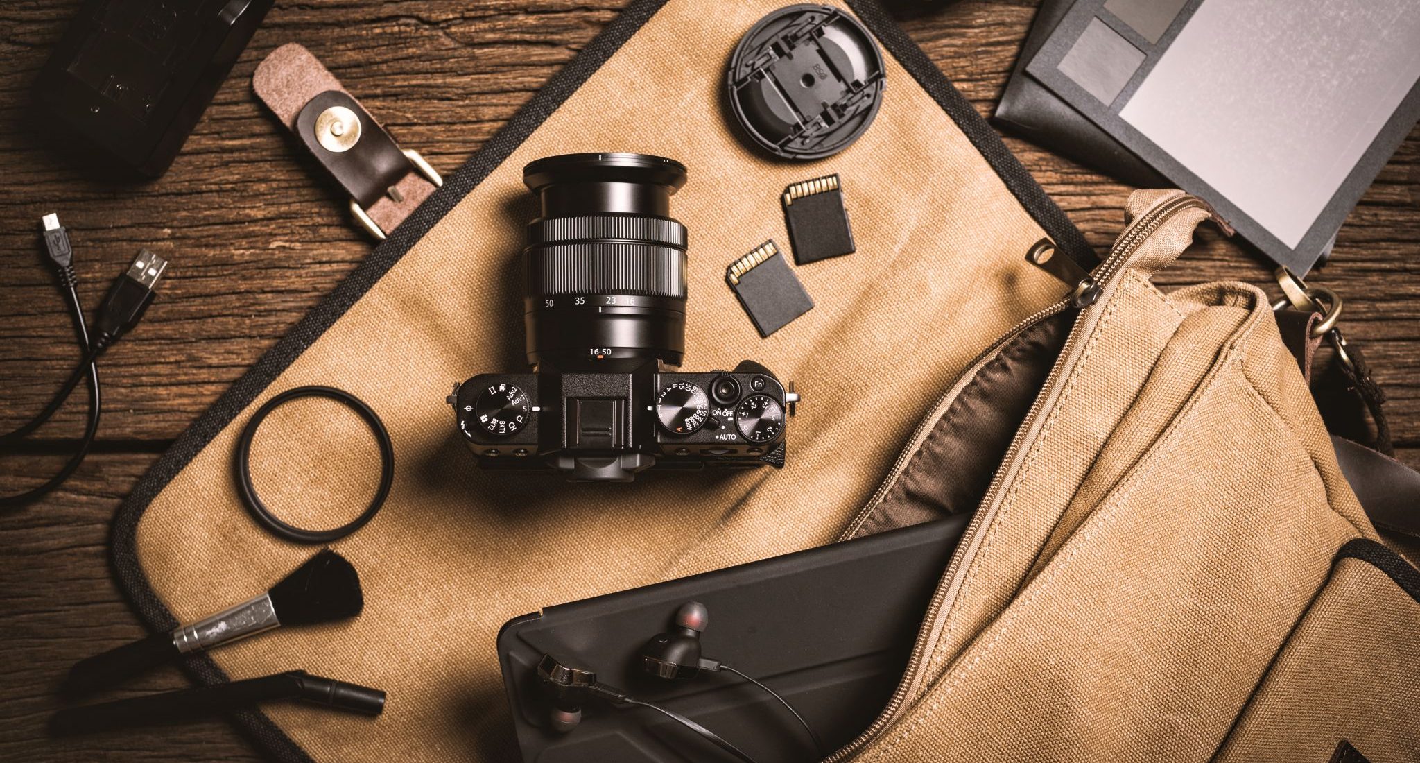 photography gear on wooden table, digital camera lens and other accessories.